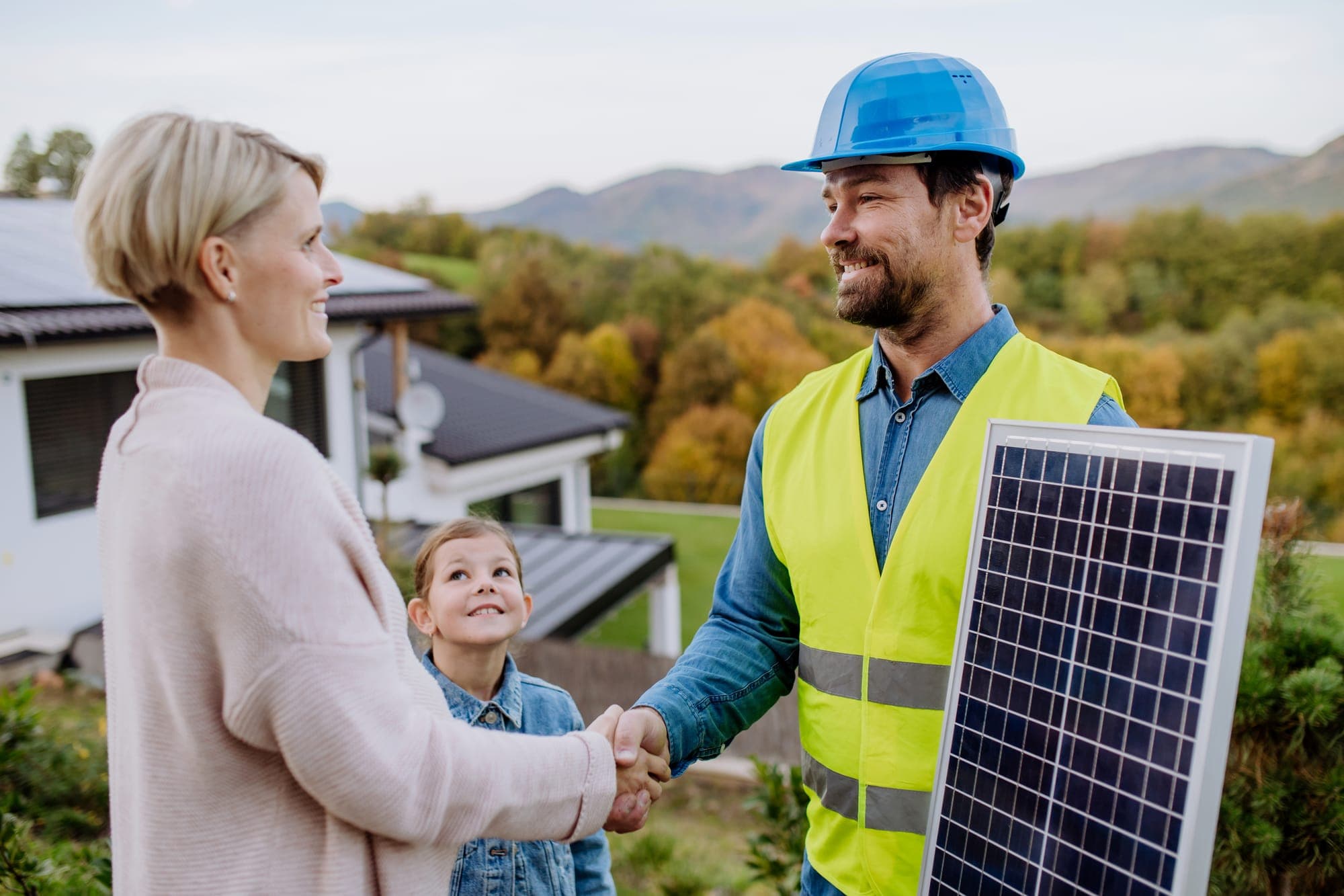 Técnico estrechando la mano a una familia tras instalar sus placas solares